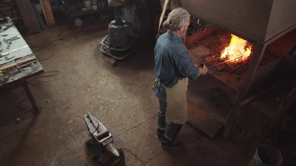 Blacksmith Tending Forge Fire in Smithy alt