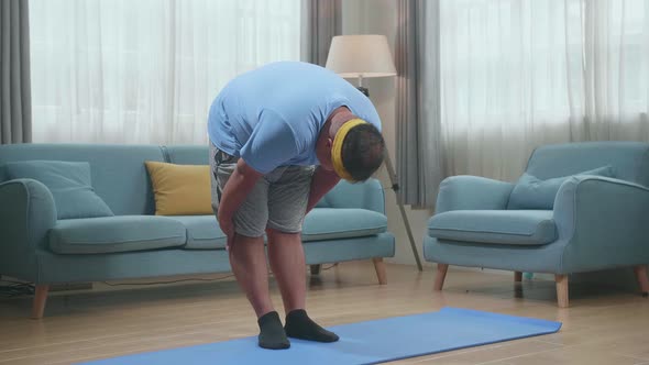 Fat Asian Man On Mat Doing Yoga By Half Standing Forward Bend At Home alt
