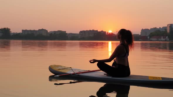 Young Woman Doing Yoga on SUP Board at Sunset alt