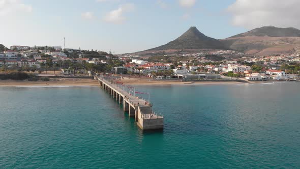 Drone flies around a walkway leading out from the island of Porto Santo. alt