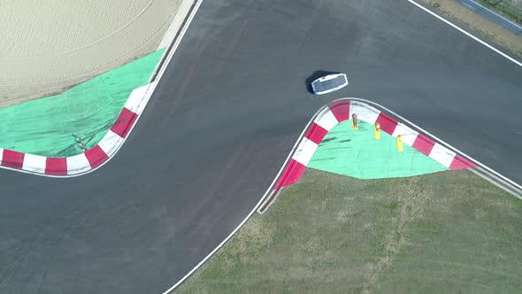 Solar Powered Car Driving on Closed Track Followed By Black Vehicle, Aerial Top Down alt