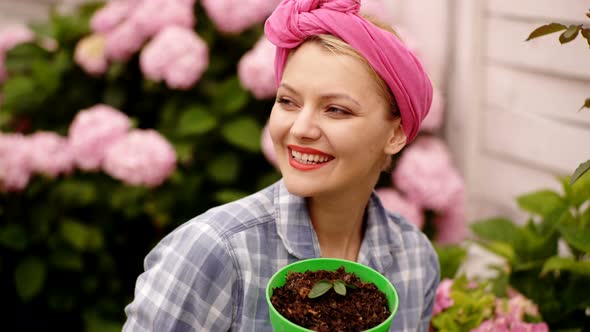 Female Gardener Planting Flowers in Pots. Smiling and Happy Woman Cares for Flowers. Concept of Care alt