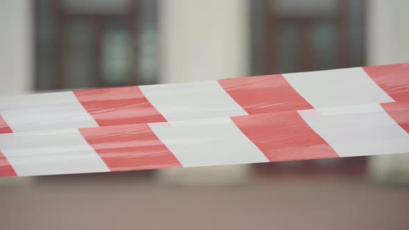 Close-up of Red and White Barricade Tape with Blurred Urban Building at the Background. City alt