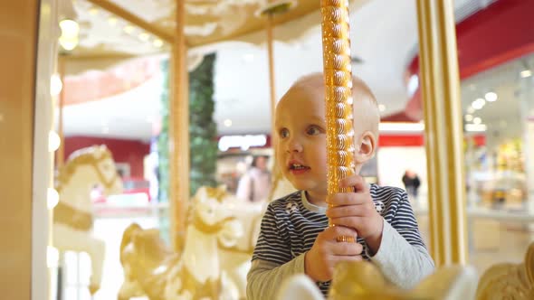 Close Up View of Little Babyboy is in Great Delight From Riding on the Carousel