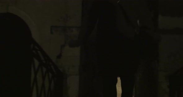 Woman running in dark alleyway at night alt