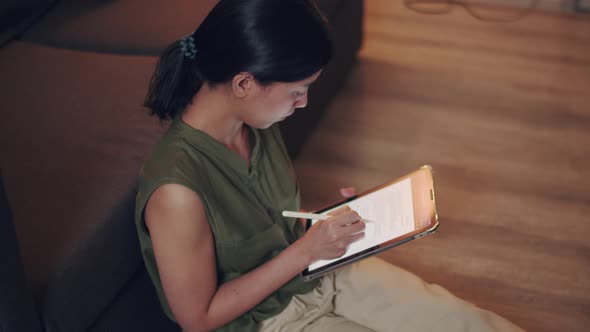 Asian woman reading news on her digital tablet.