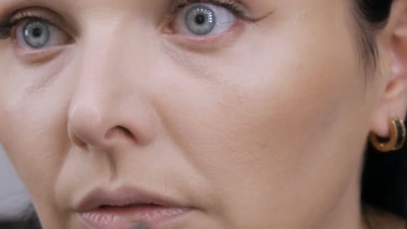 Young Beautiful Showy Woman in Front of the Mirror Applies Face and Eye Makeup with a Special Brush alt