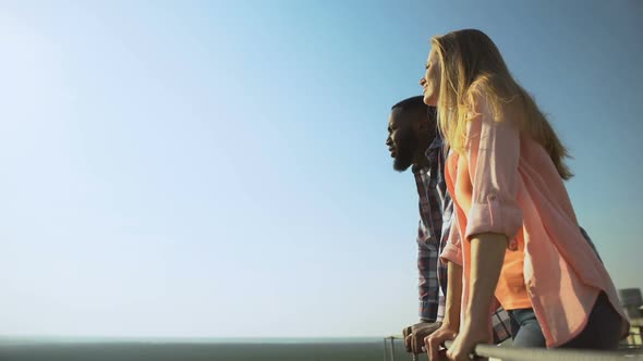 Cheerful Multiethnic Couple Talking and Enjoying Cityscape on Observation Deck