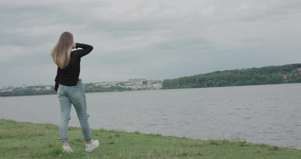 Happy Girl on Seaside Walk Turns at Camera Posing with Her Hair and Smiling alt