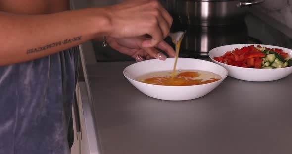 Young woman stirring eggs with fork close-up.