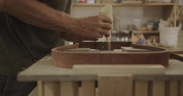 Luthier Applying glue on an instrument