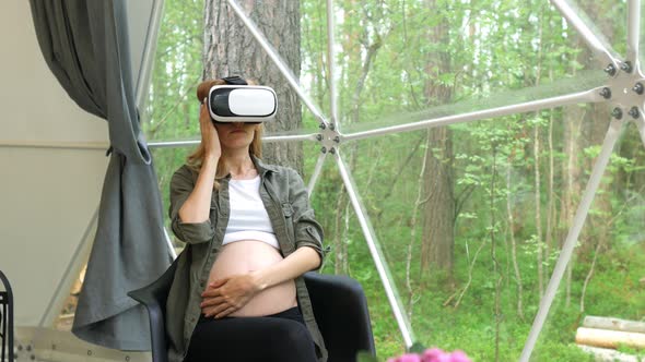 pregnant in virtual reality glasses stroking stomach overlooking the forest alt