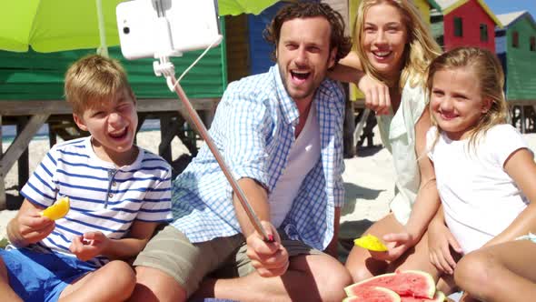 Family taking selfie on mobile phone at beach alt