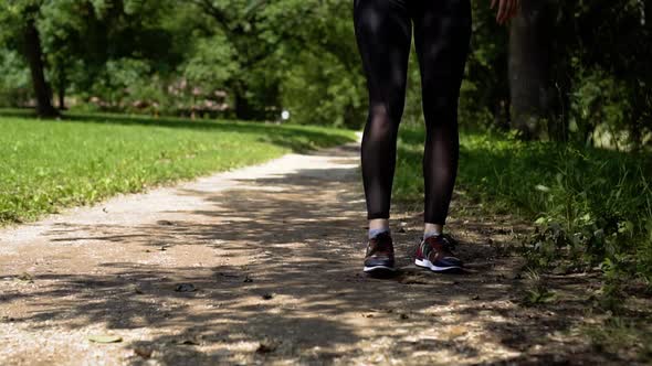 Girl Laces Up Sneakers on Nature Green Park