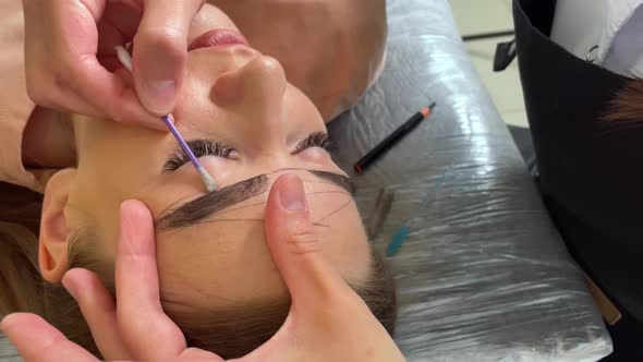 Beauty Master Draws a Contour of Eyebrows on a Young Girl