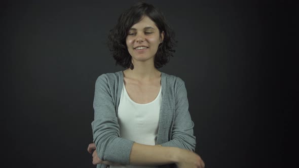 Young Woman in White Top Under Grey Jumper Poses with Smile alt
