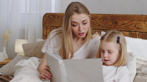 Young Caring Mother Mom Woman Lies Sitting with Little Daughter Preschool Girl in Bed Together in alt