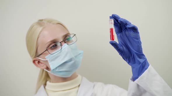 A Medical Professional Holds a Test Tube with a Blood Test and Examines It for Defects