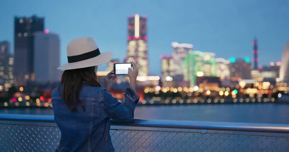 Woman take photo with cellphone in Yokohama city at night alt