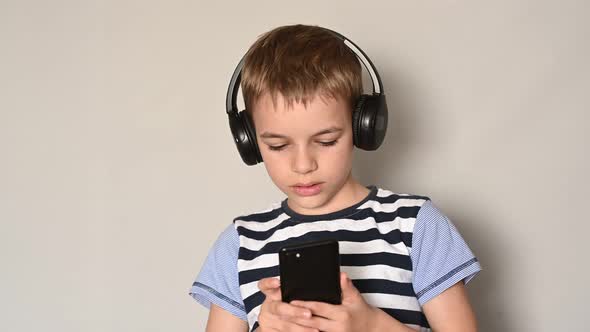 Teenage Boy Texting Using Smartphone Listening To Music Wearing Headphones