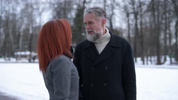 gray-haired tall man talking to a young woman on the street alt
