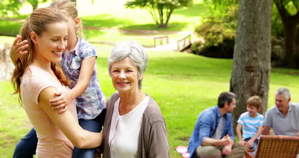 Three generations of women smiling at camera with men behind alt