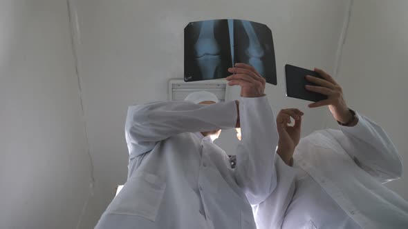 Male Medics Using Tablet Pc While Consult with Each Other About x Ray Image of Patient alt