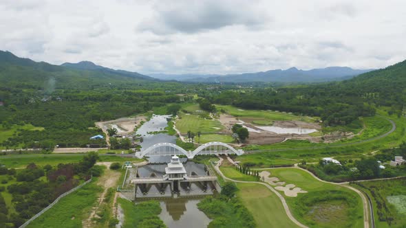 Aerial top view of Tha Chomphu White Bridge, Lamphun, Thailand with lake or river alt