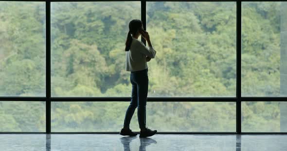 Businesswoman use of mobile phone and walking over the glass window alt