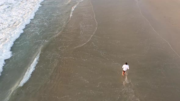 Aerial shot of young man running on the beach. alt