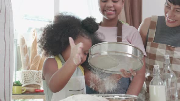 Happy moment of African American family sifting the bread flour on weekend