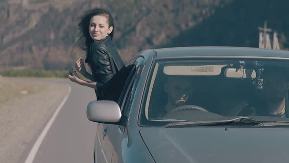 Wind Plays with Young Lady Hair Leaning Out of Driving Car alt