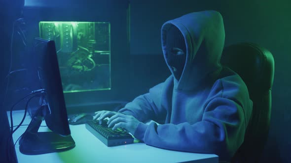 Cybercriminal Hacker in Black Mask Typing on Keyboard