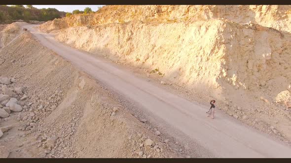 Beautiful Young Woman Walks Barefoot on a Sandy Road Among the Rocks and Stones alt