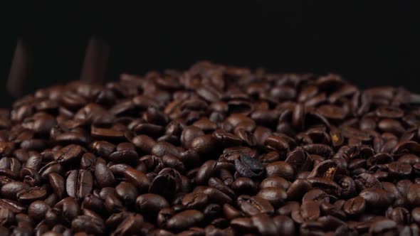 slow motion of roasted coffee beans falling down and rotating on black background