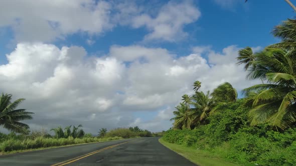 POV Driving Along Two Lane Road on Tropical Island Against Blue Sky and Clouds