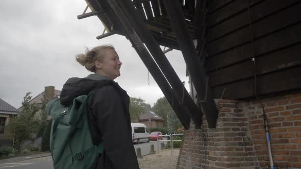 Slow motion footage of a female traveler observing the architecture underneath an old windmill in th alt
