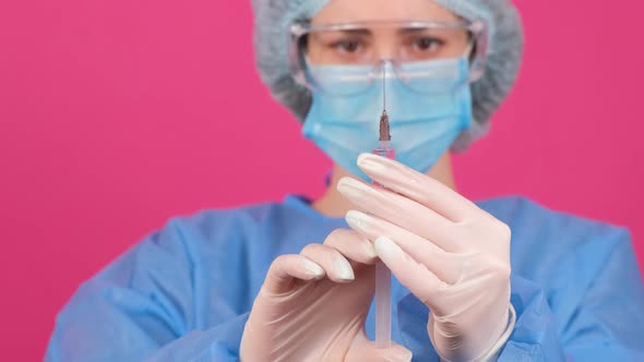 Professional Woman Doctor Holds a Syringe with a Vaccine on a Pink Background alt