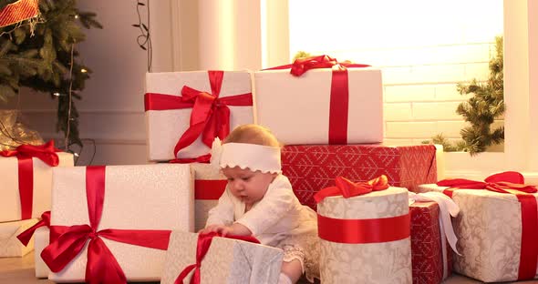 A Little Girl Child is Sitting Among the Gifts Looking at