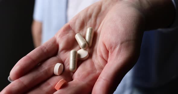 Woman hold different pills in hand before taking them , close up of medicament daily dose pill alt
