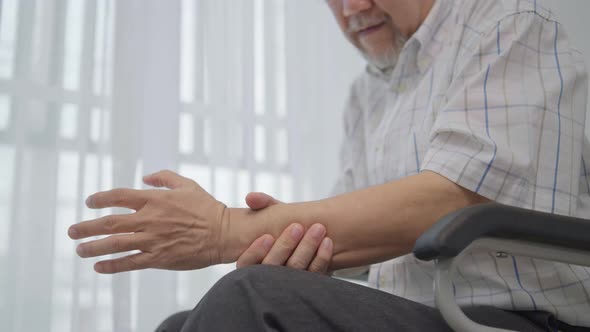 Senior man massaging wrist and arm to relieve suffering from joint pain