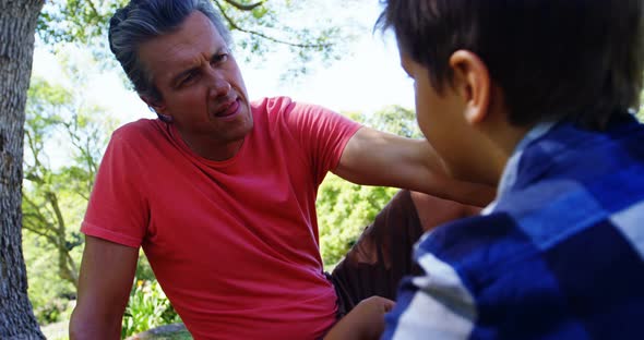Father consoling his son at picnic in park 4k alt