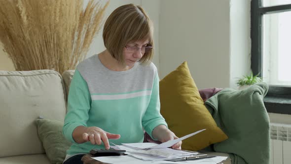 Senior Mature Woman Using Calculator Holding Paper Bill Calculating Money Budget Tax alt