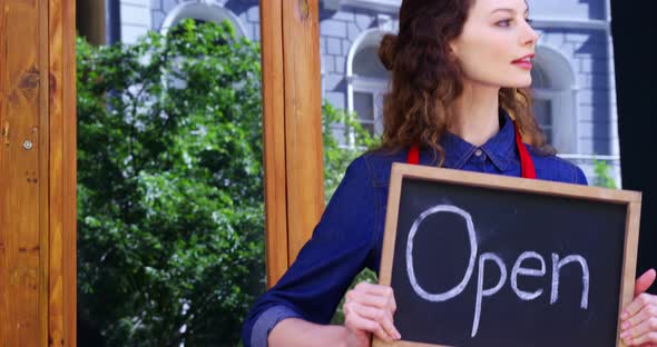 Smiling waitresses holding open sign board alt