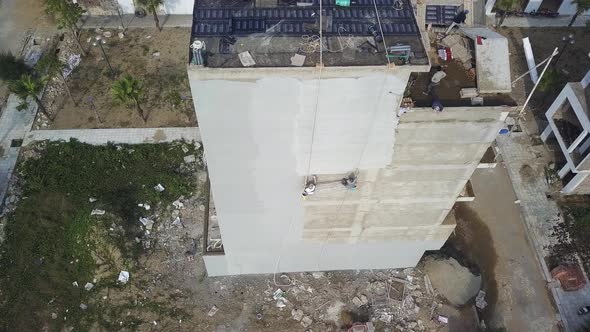 Concrete plaster finish applied to building side in Sam Son Vietnam as two construction workers swin alt