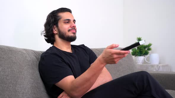 Tired Indian man watching TV late at night alt