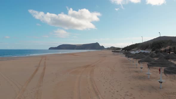 Sun umbrellas on empty beach, Porto Santo in Madeira. Aerial forward alt