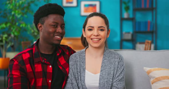 Camera Approaching Happy Family Coupe Looking at Camera and Smiling in Good Mood While Sitting alt