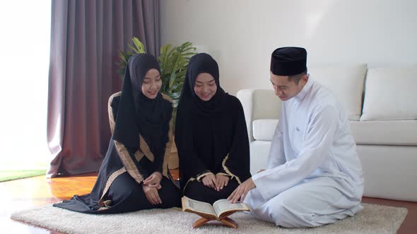 Handsome Muslim man explaining two young women read Quran 