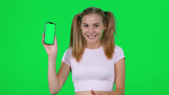 Cheerful Caucasian Female Holds a Smartphone in Her Hands and Shows It to the Camera Beautiful alt